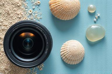 Creative beach photography setup with seashell and camera lens